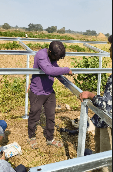 A worker assembling a galvanised steel solar mounting structure in a field